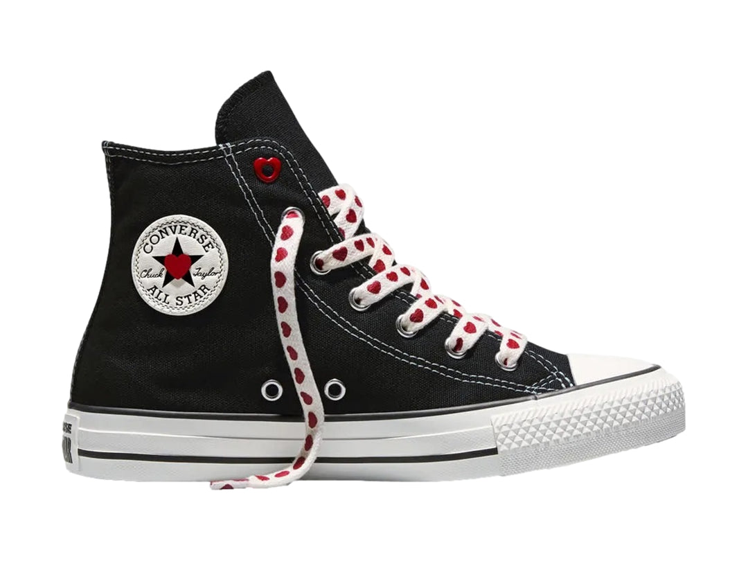 Tenis Converse negros de bota alta con suela blanca y agujetas blancas decoradas con corazones rojos.