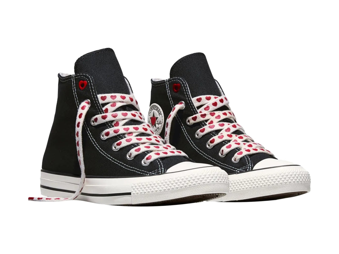 Tenis Converse negros de bota alta con suela blanca y agujetas blancas decoradas con corazones rojos.