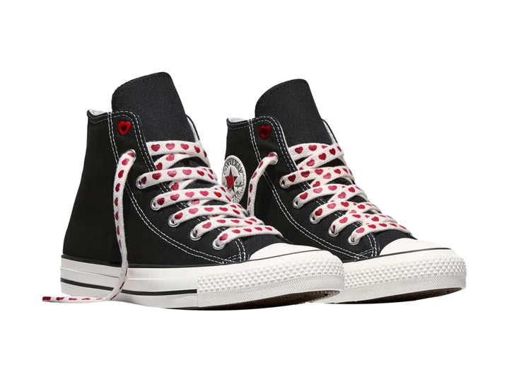 Tenis Converse negros de bota alta con suela blanca y agujetas blancas decoradas con corazones rojos.