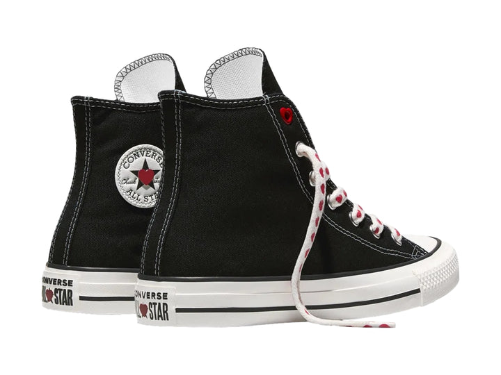 Tenis Converse negros de bota alta con suela blanca y agujetas blancas decoradas con corazones rojos.