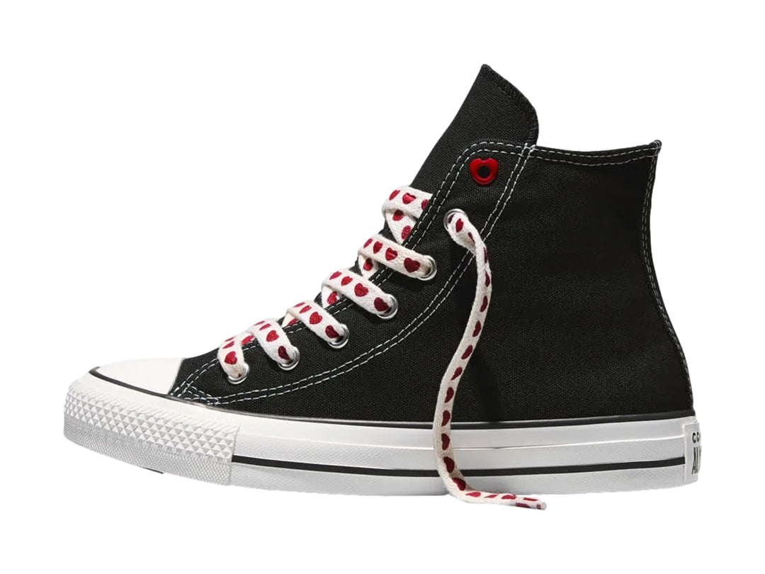 Tenis Converse negros de bota alta con suela blanca y agujetas blancas decoradas con corazones rojos.