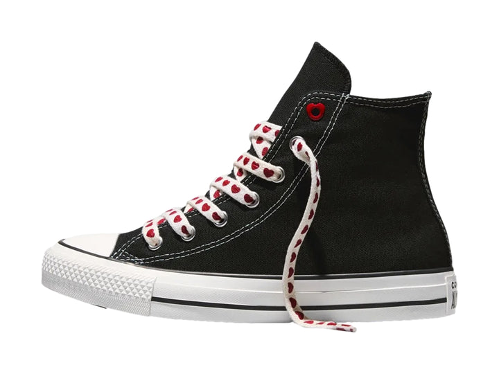 Tenis Converse negros de bota alta con suela blanca y agujetas blancas decoradas con corazones rojos.