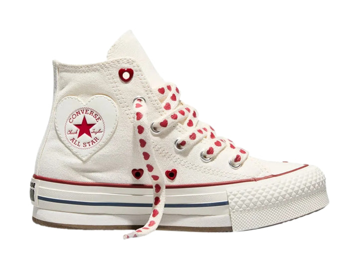 Tenis Converse blancos de bota alta con plataforma, agujetas decoradas con corazones rojos y detalles en rojo y azul.
