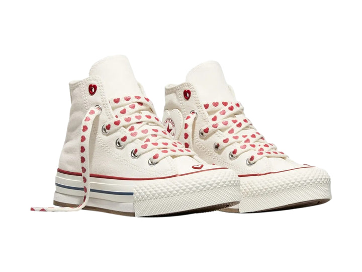 Tenis Converse blancos de bota alta con plataforma, agujetas decoradas con corazones rojos y detalles en rojo y azul.