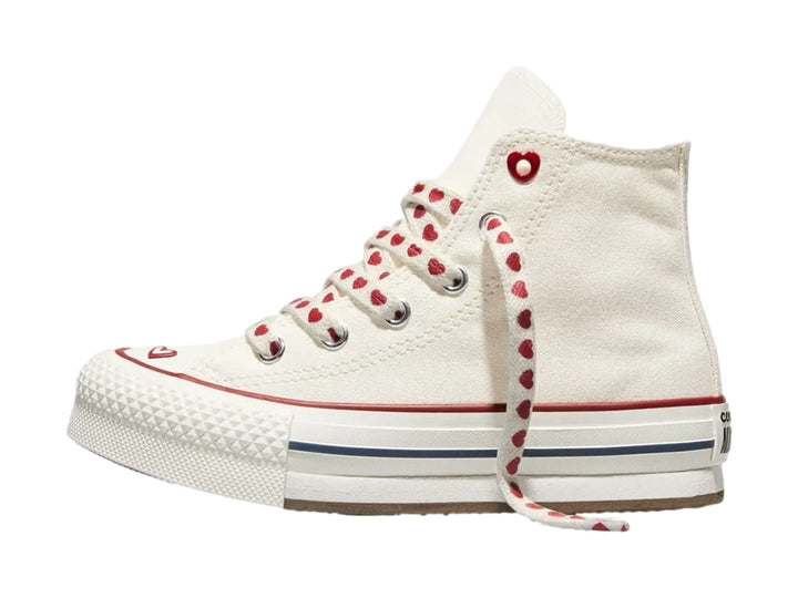 Tenis Converse blancos de bota alta con plataforma, agujetas decoradas con corazones rojos y detalles en rojo y azul.