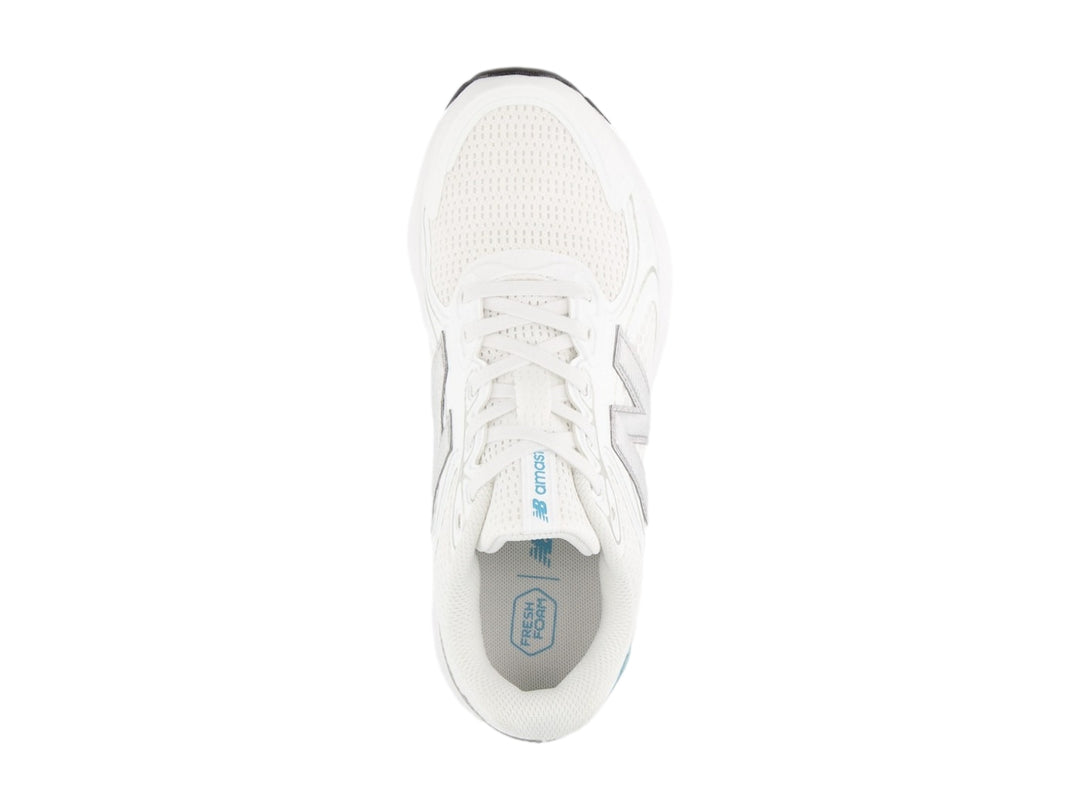 Tenis New Balance color blanco con detalles en gris y azul, diseño deportivo de malla transpirable.