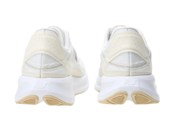 Tenis New Balance color blanco con detalles en morado y suela blanca robusta.
