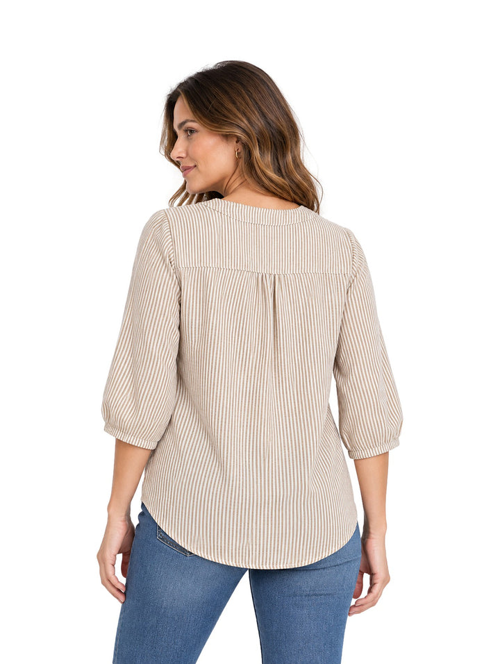 Mujer vistiendo blusa beige a rayas verticales con cuello en V y botones, combinada con jeans azules.