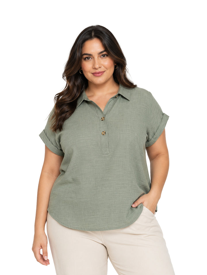 Mujer vistiendo blusa color verde oliva claro con botones frontales y manga corta.