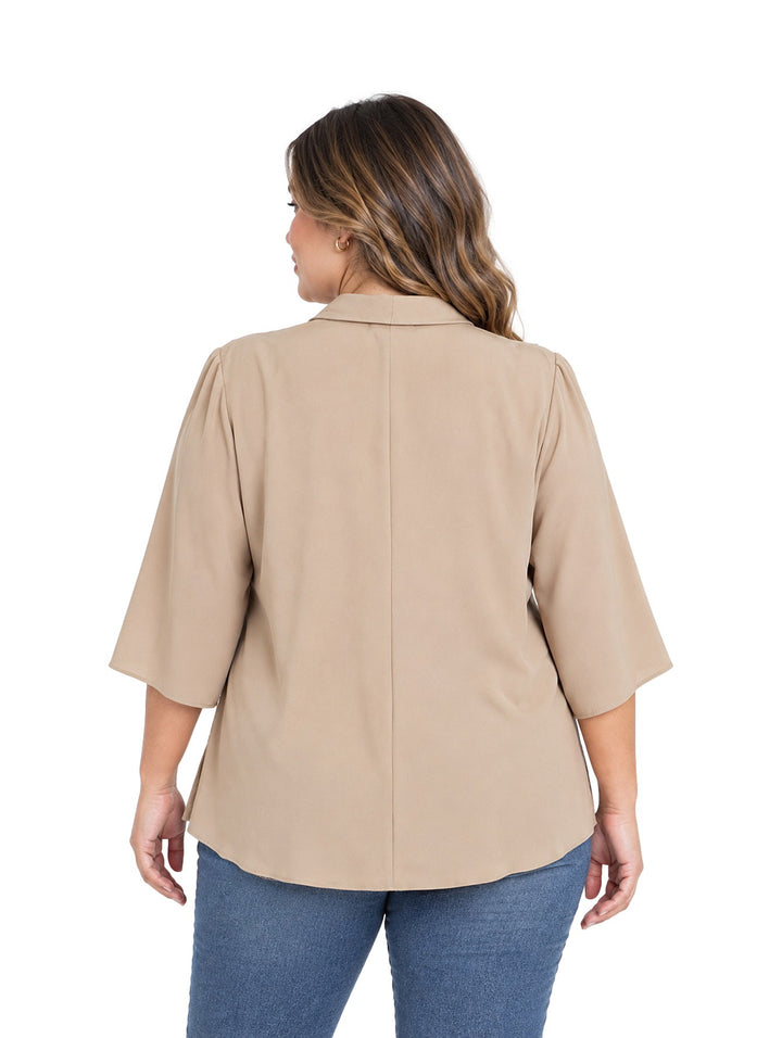 Mujer vistiendo blusa color taupe de corte curvy con cuello anudado y mangas tres cuartos.