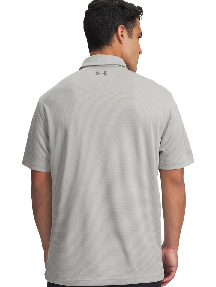 Hombre vistiendo una playera polo Under Armour de color gris con cuello y manga corta.