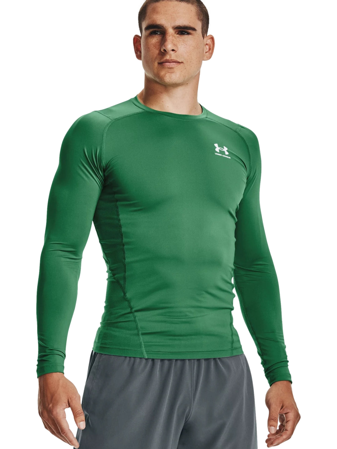 Hombre vistiendo una camiseta deportiva de compresión color verde de manga larga de la marca Under Armour.