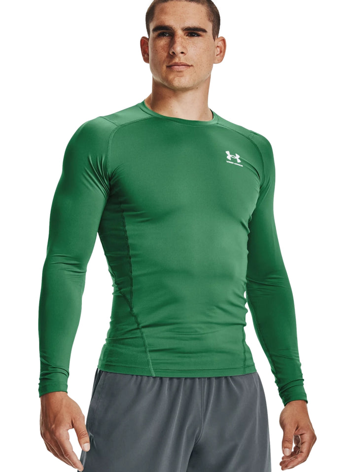 Hombre vistiendo una camiseta deportiva de compresión color verde de manga larga de la marca Under Armour.