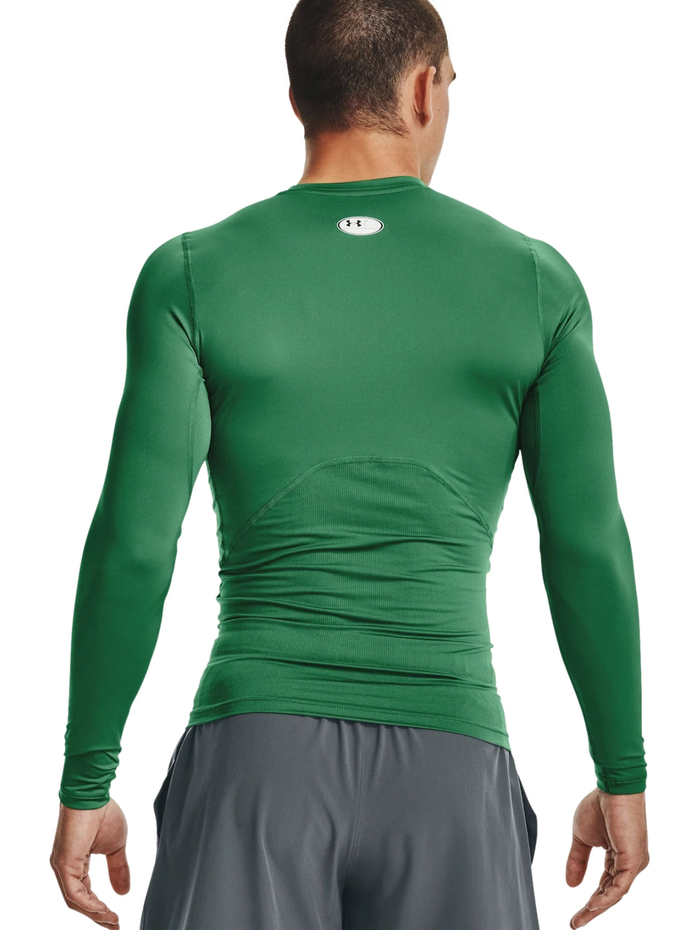 Hombre vistiendo una camiseta deportiva de compresión color verde de manga larga de la marca Under Armour.