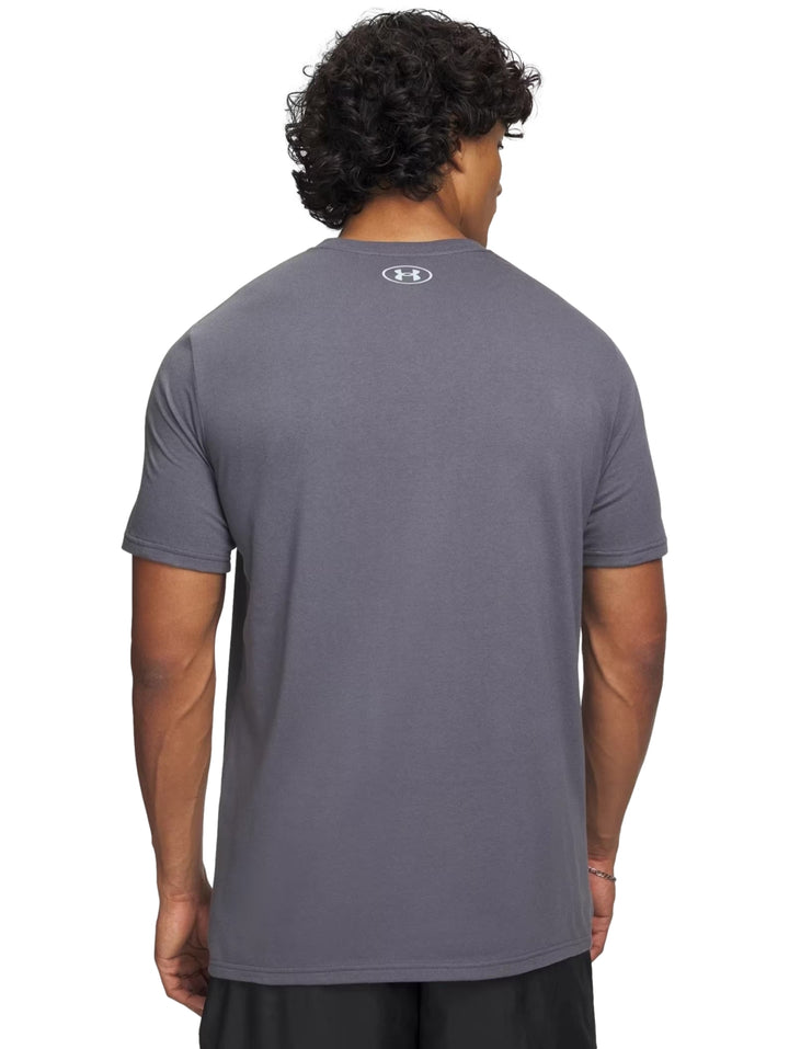 Hombre vistiendo camiseta deportiva gris de manga corta con logotipo de Under Armour en el pecho.