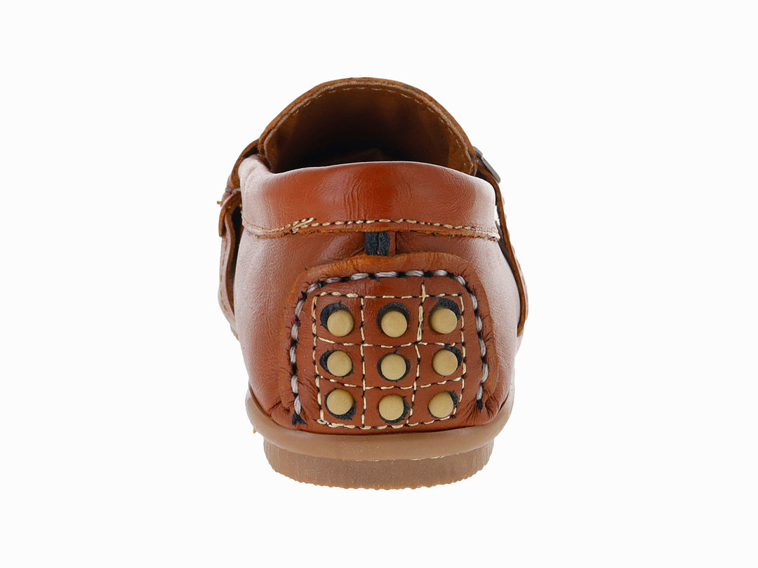 Zapato tipo mocasín para niño en piel color camel con costuras blancas y adorno metálico en el empeine.