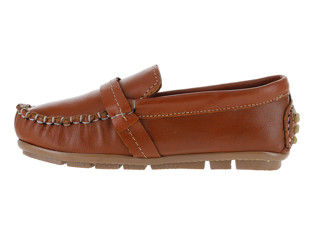 Zapato tipo mocasín para niño en piel color camel con costuras blancas y adorno metálico en el empeine.
