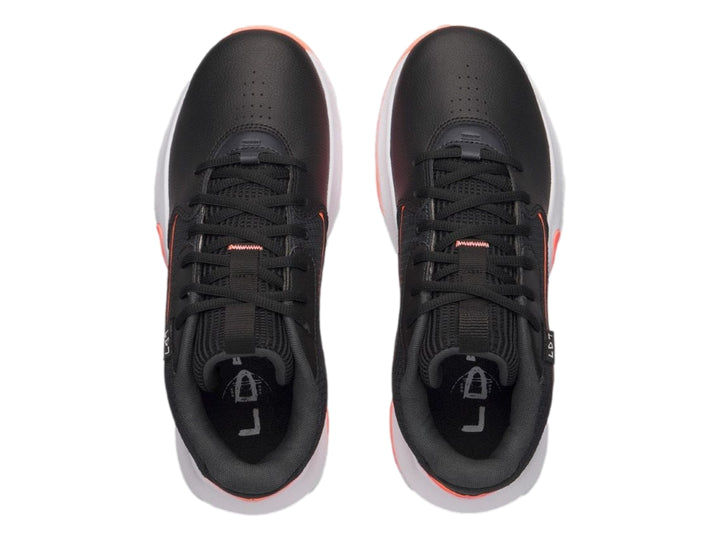 Tenis de baloncesto Under Armour color negro con detalles en naranja y suela blanca.