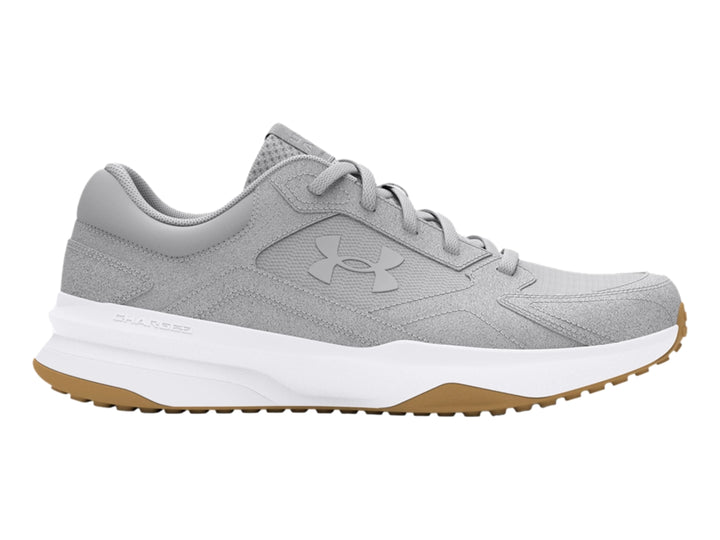 Tenis Under Armour color gris con suela blanca y detalle café en la base, diseño deportivo de gamuza.