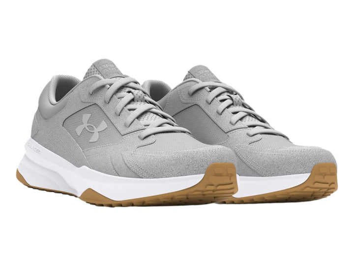 Tenis Under Armour color gris con suela blanca y detalle café en la base, diseño deportivo de gamuza.