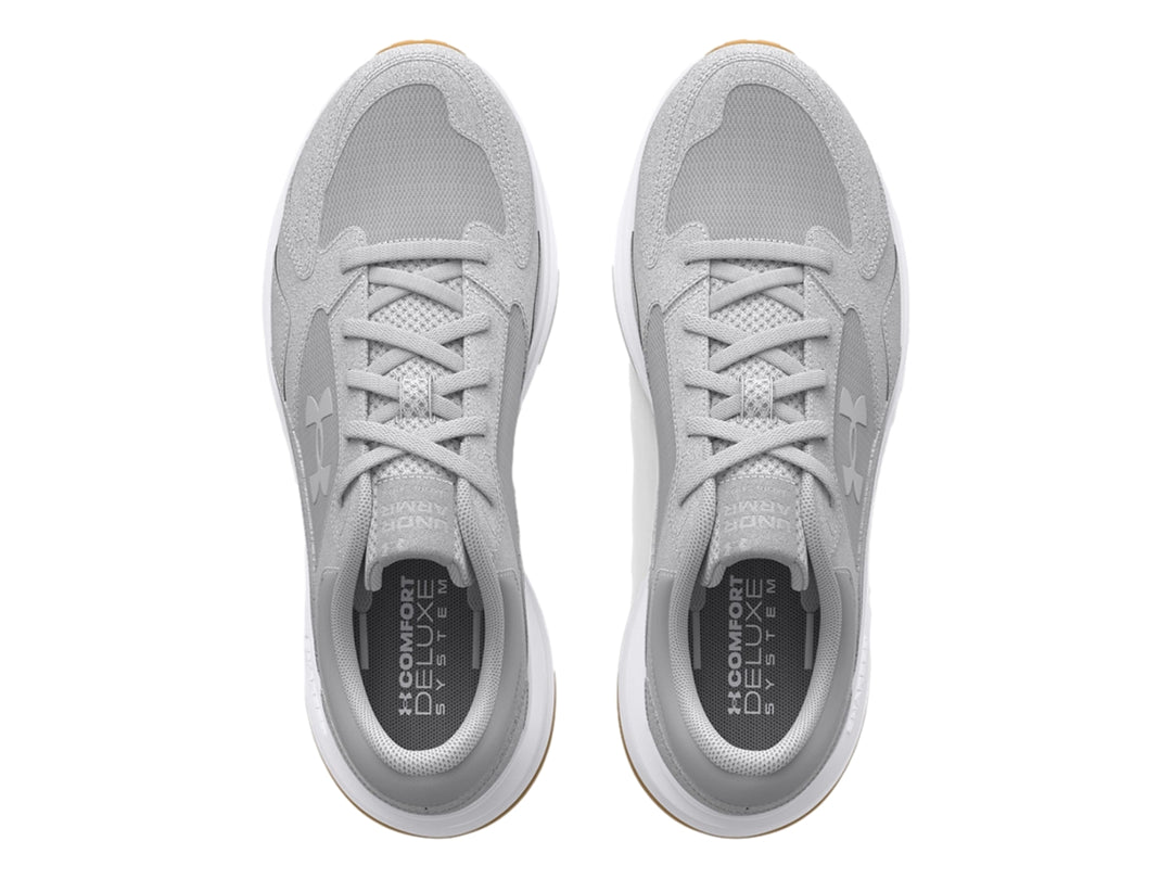 Tenis Under Armour color gris con suela blanca y detalle café en la base, diseño deportivo de gamuza.