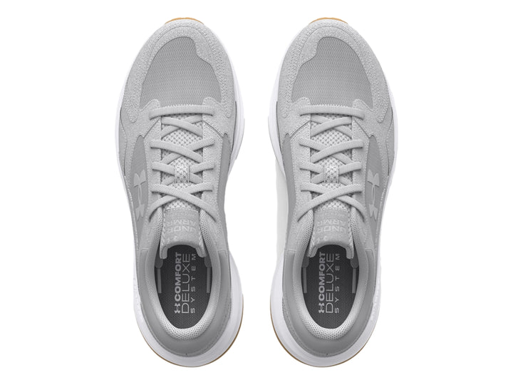 Tenis Under Armour color gris con suela blanca y detalle café en la base, diseño deportivo de gamuza.