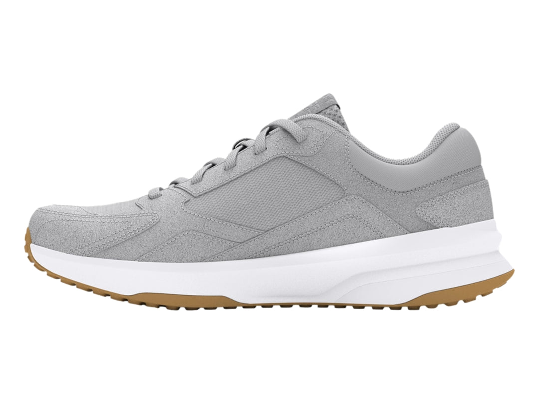 Tenis Under Armour color gris con suela blanca y detalle café en la base, diseño deportivo de gamuza.