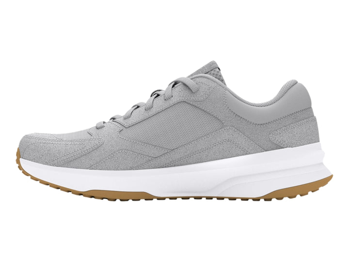 Tenis Under Armour color gris con suela blanca y detalle café en la base, diseño deportivo de gamuza.