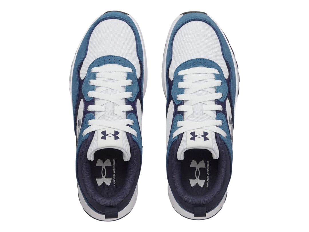 Tenis deportivos Under Armour en tonos azul y blanco con suela blanca y detalles negros.
