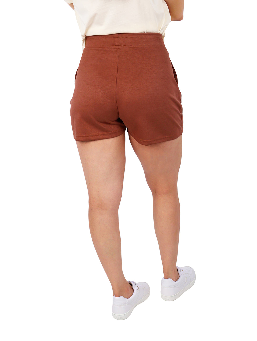 Mujer vistiendo shorts deportivos color marrón con bolsillos y cintura elástica.