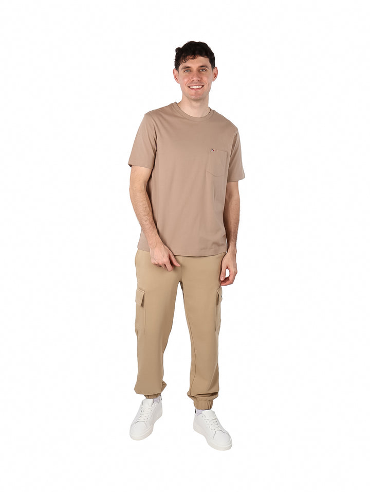 Hombre vistiendo una camiseta de manga corta color taupe con un pequeño bolsillo en el pecho.