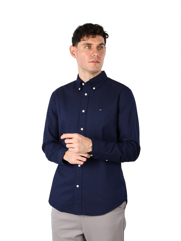 Hombre vistiendo una camisa Tommy Hilfiger de color azul marino con botones blancos y manga larga.