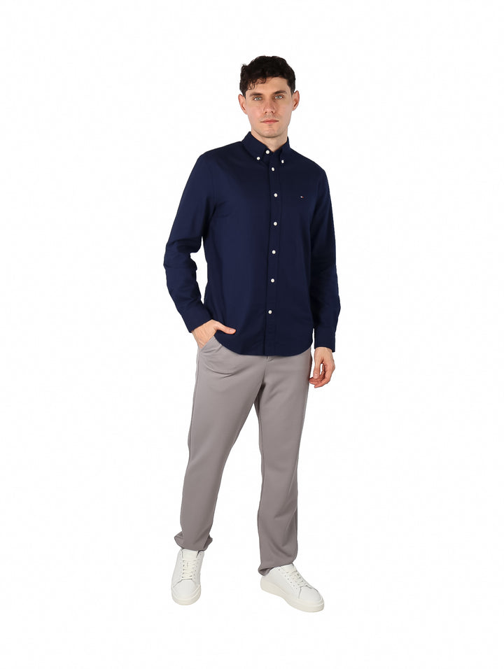 Hombre vistiendo una camisa Tommy Hilfiger de color azul marino con botones blancos y manga larga.