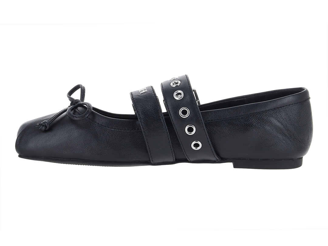 Zapato plano negro con dos hebillas plateadas y un moño decorativo en la punta.