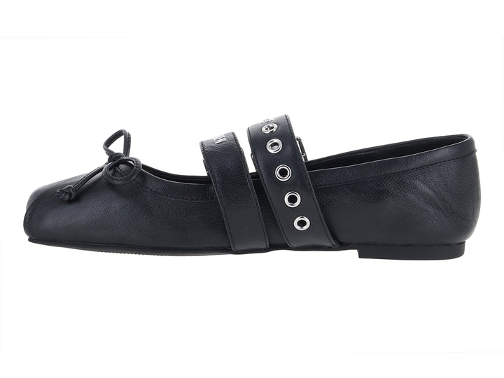 Zapato plano negro con dos hebillas plateadas y un moño decorativo en la punta.