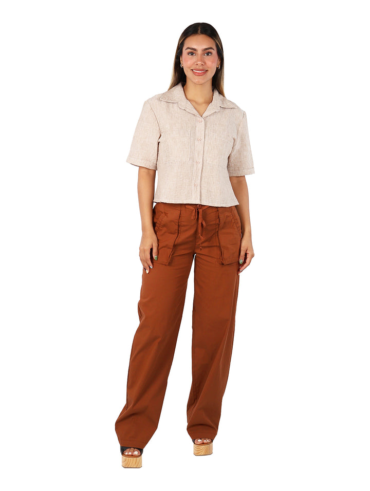 Mujer vistiendo una blusa camisera de color beige con manga corta y botones frontales.