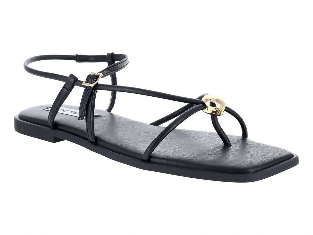 Sandalias planas negras con tiras y hebillas doradas de la marca Steve Madden.