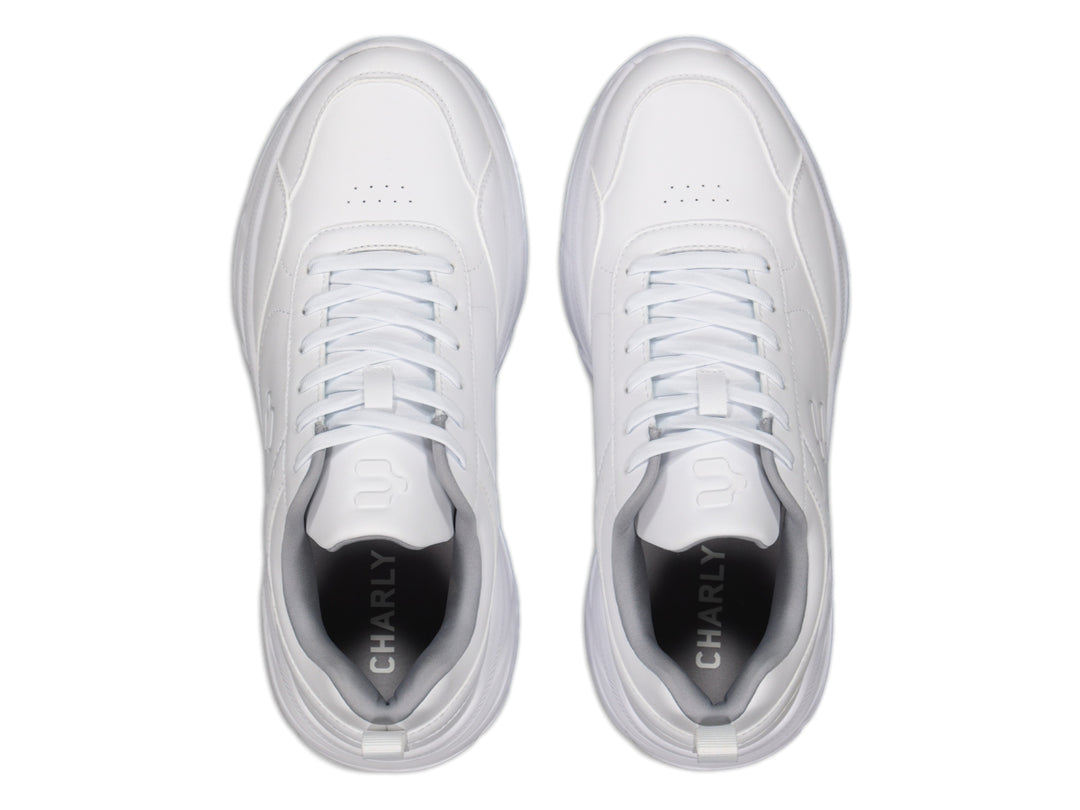 Tenis deportivos Charly color blanco con suela robusta y cordones, vista lateral sobre fondo blanco.