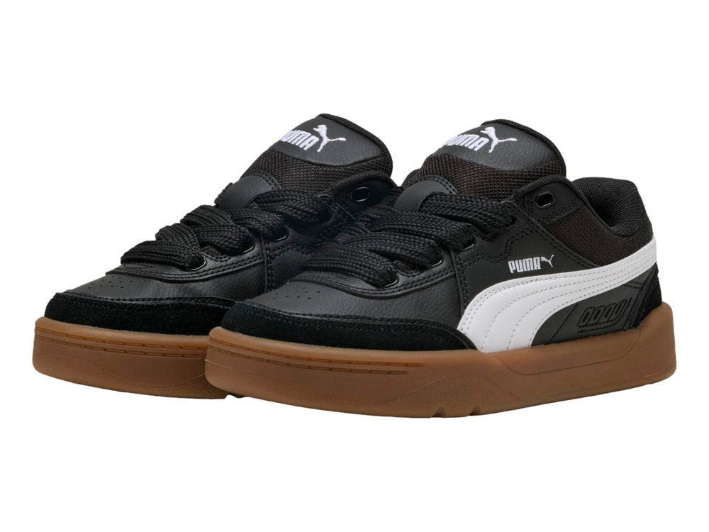 Tenis PUMA negros para niños con suela color café y franja blanca lateral.