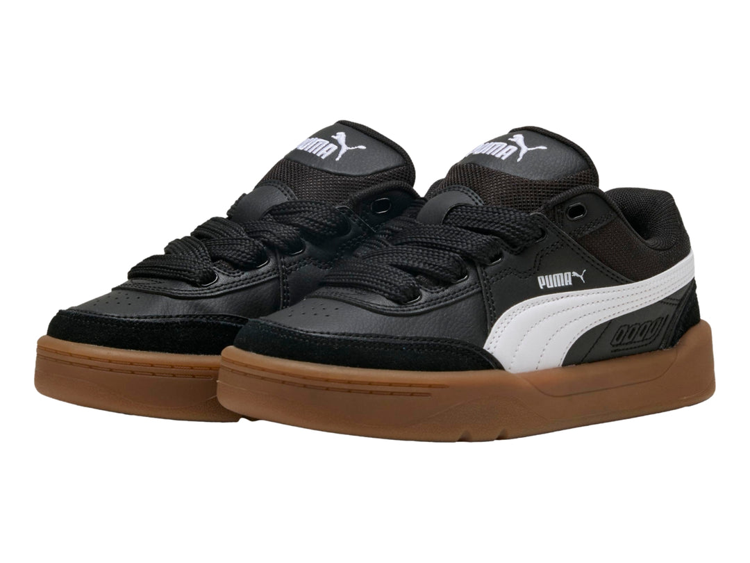 Tenis PUMA negros para niños con suela color café y franja blanca lateral.