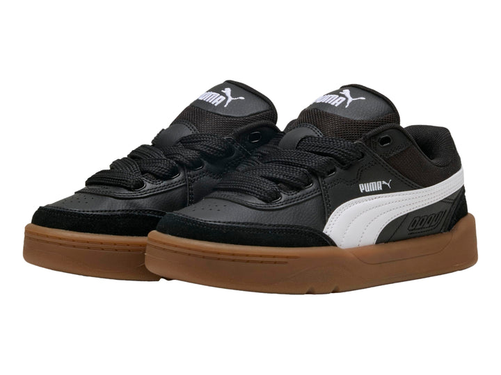 Tenis PUMA negros para niños con suela color café y franja blanca lateral.