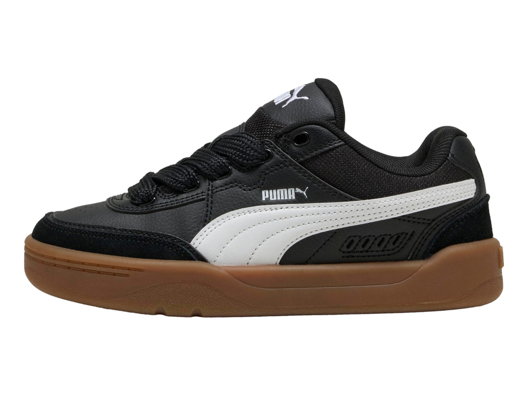 Tenis PUMA negros para niños con suela color café y franja blanca lateral.