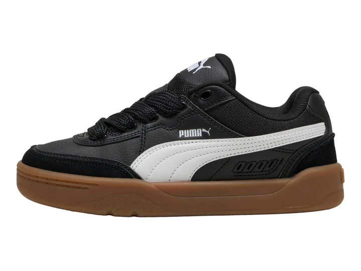 Tenis PUMA negros para niños con suela color café y franja blanca lateral.
