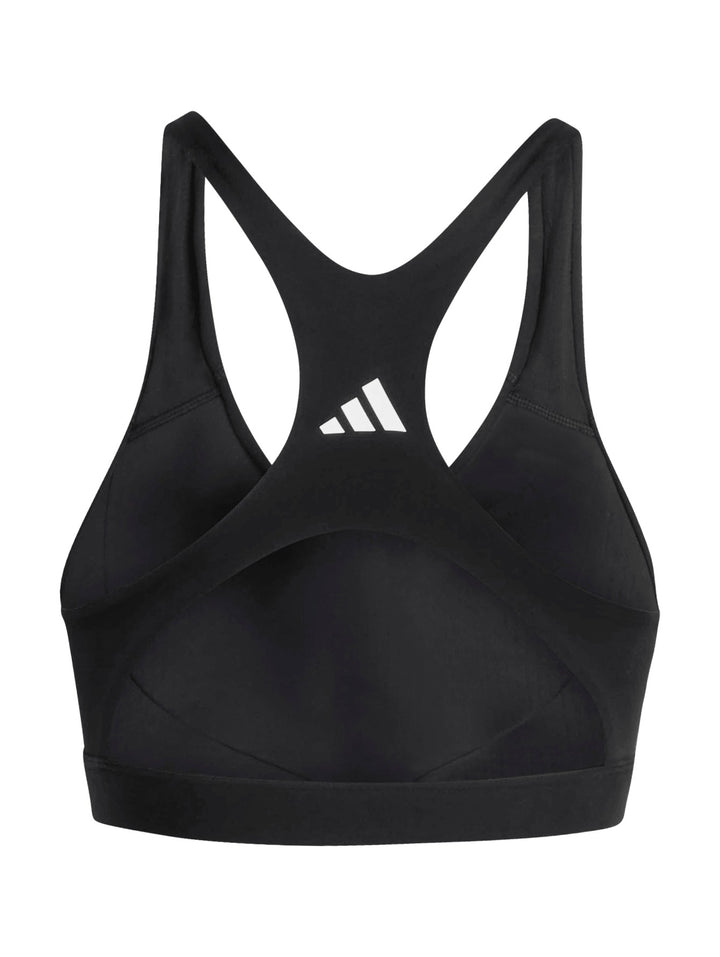 Mujer vistiendo un top deportivo corto color negro de la marca Adidas sobre fondo blanco.
