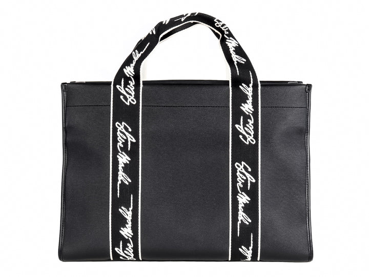 Bolso tote negro Steve Madden con bandas verticales blancas y asas largas coordinadas.