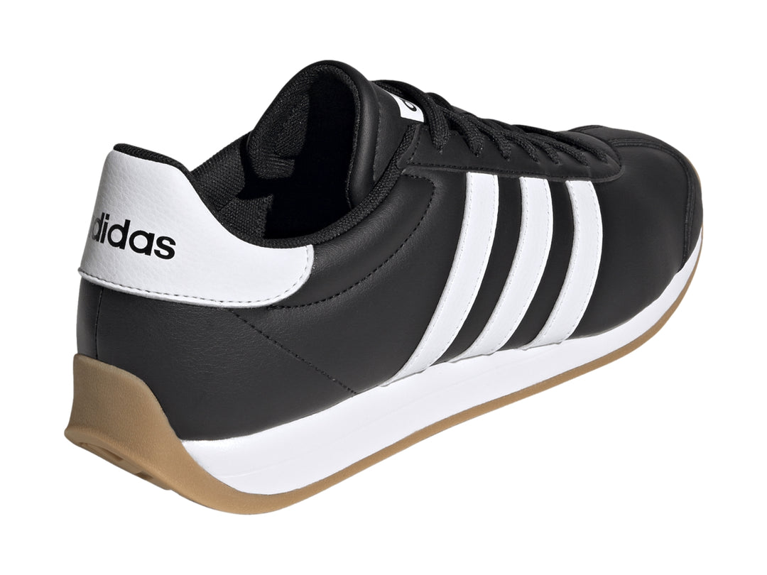 Tenis Adidas Runvista color negro con tres franjas blancas y suela de goma marrón.