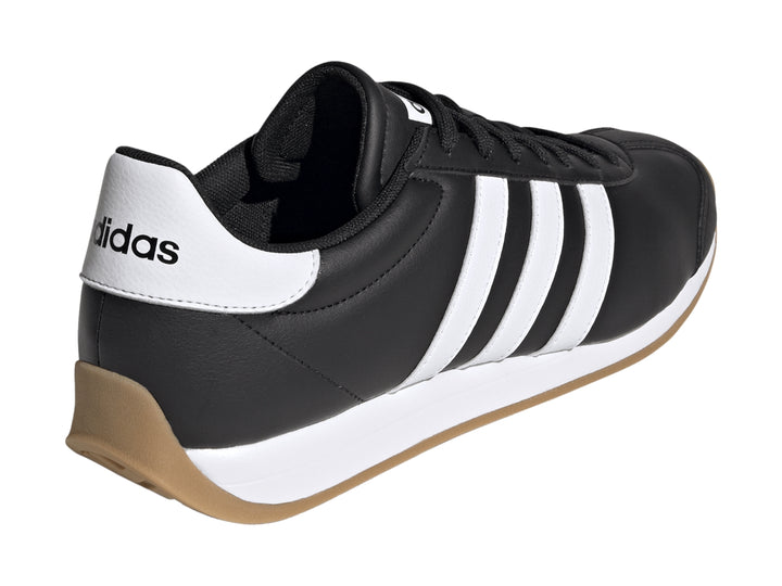 Tenis Adidas Runvista color negro con tres franjas blancas y suela de goma marrón.