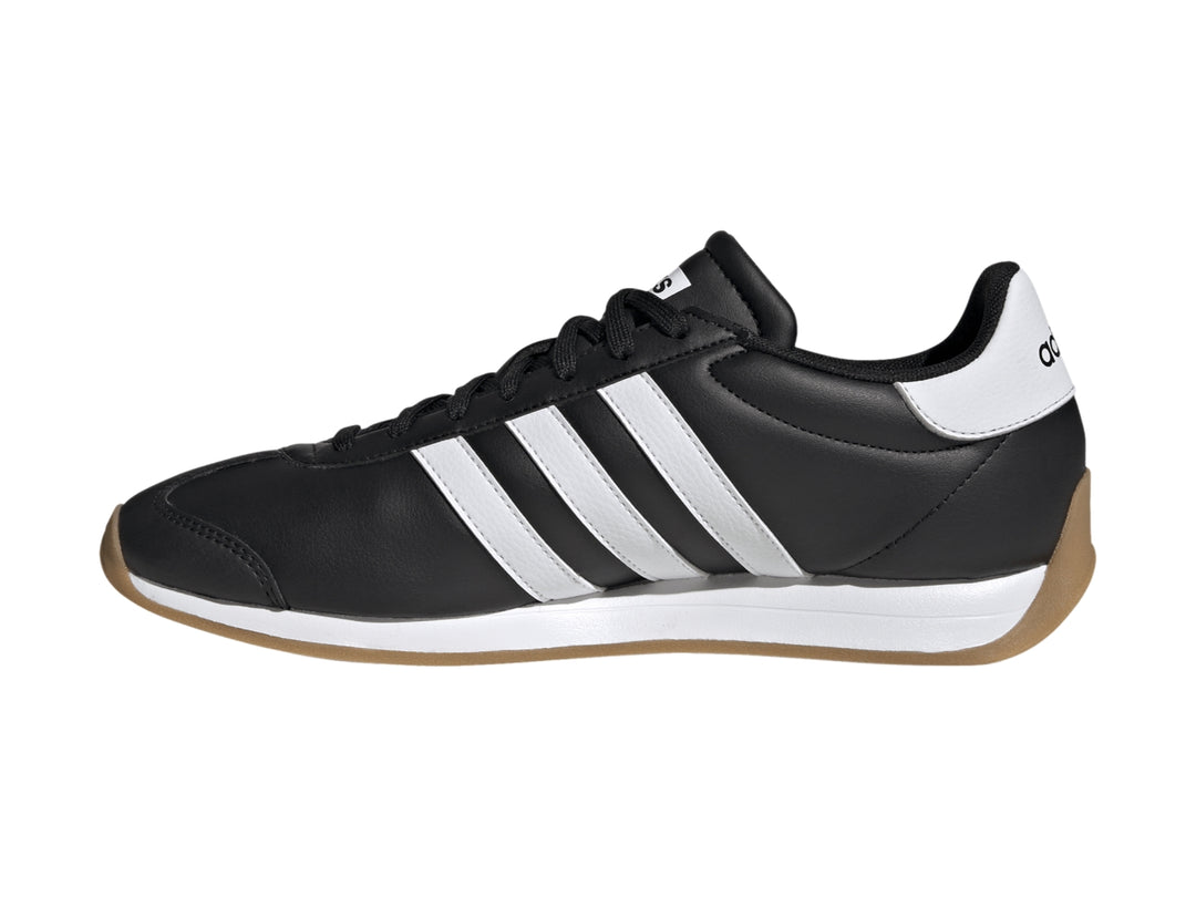Tenis Adidas Runvista color negro con tres franjas blancas y suela de goma marrón.