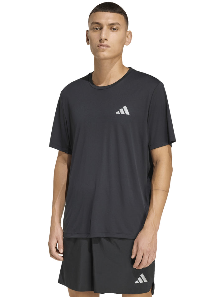 Hombre vistiendo camiseta deportiva de color negro con logo de Adidas en el pecho.