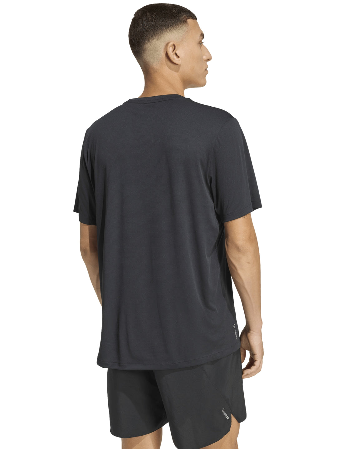 Hombre vistiendo camiseta deportiva de color negro con logo de Adidas en el pecho.